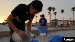 Residentes de Long Beach, California, llenan sacos de arena en espera del huracán Hilary el19 de agosto de 2023.