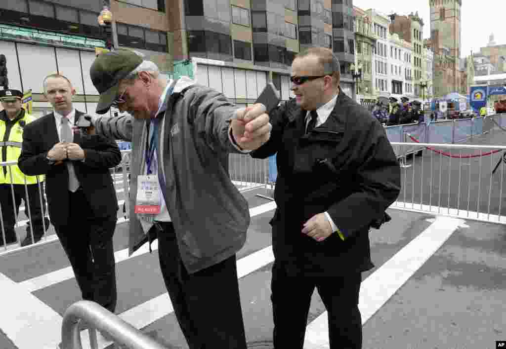 A law enforcement official searches a man near the finish line of the Boston Marathon in anticipation of the arrival of Vice President Joe Biden, April 15, 2014.