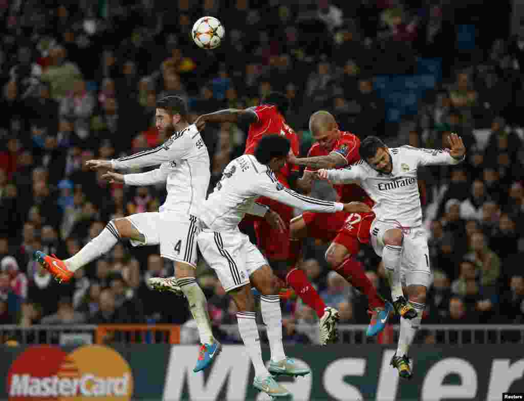 Các cầu thủ của đội Liverpool và Real Madrid nhảy lên chặn bóng trong một trận bóng đá Bảng B của giải Champions League ở Madrid. 