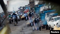 FILE - A reflection from the wing mirror of a car shows people ride motorcycles in Douala.