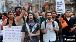 FILE - Demonstrators shout slogans as they clash with riot police on Istiklal Street in central Istanbul, July 13, 2013. 