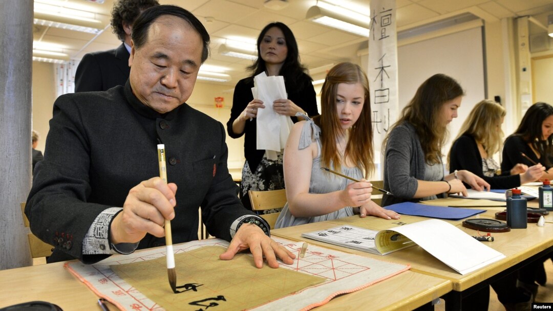 Mo Yan, Chinese winner of the 2012 Nobel Prize in Literature, demonstrates Chinese calligraphy to a student during a visit to a high school in Lidingo, outside Stockholm, Dec. 7, 2012. 
