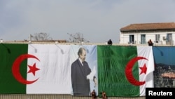 Des employés de la ville installe le drapeau algérien et un poster du président Abdelaziz Bouteflika, à Alger, en Algérie, le 26 avril 2016.