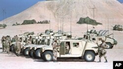 FILE - U.S. Marines tend to a row of parked humvees with TOW anti-tank missile launchers mounted on them at a desert camp in Saudi Arabia during the Gulf War, Jan. 26, 1991. 