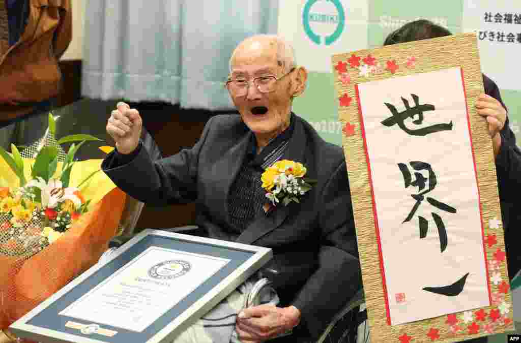 In this Japan picture received through Jiji Press, 112-year-old Chitetsu Watanabe stands next to a sign reading, in Japanese, &#39;World Number One&#39; after he was officially recognized as the world&#39;s oldest living male, in Joetsu, Niigata prefecture.