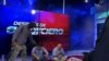 Озброєна особа в масці стоїть над журналістами під час прямого ефіру телеканалу TC Television в Еквадорі у вівторок, 9 січня 2024 р. (TC Television network via AP)