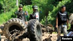 Thai security personnel inspect the wreckage of a military truck after a bomb attack by suspected Muslim militants on a roadside in Yala province, south of Bangkok June 29, 2013. Suspected Muslim rebels in southern Thailand killed eight soldiers in the ro