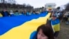 Los ucranianos y sus partidarios llevan una enorme bandera ucraniana durante una manifestación en el National Mall cerca del Monumento a Lincoln en Washington, conmemorando dos años desde la guerra. [Foto: Archivo/AP/Manuel Balce Ceneta]. 