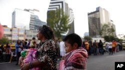 People stand in the street after hearing an earthquake alarm, in Mexico City, Saturday, Sept. 23, 2017. 