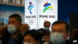 FILE - Attendees wearing face masks to protect against the spread of the coronavirus look at an exhibit at a visitors center at the Winter Olympic venues in Yanqing, on the outskirts of Beijing, Feb. 5, 2021. 