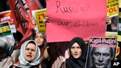 Manifestantes en Estambul portan carteles y una foto representando al presidente ruso, Vladimir Putin, durante una protesta contra las operaciones militares rusas en Siria, el sábado, 3 de octubre de 2015.