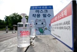 FILE - Bottles of hand sanitizer are displayed for use at a park in Goyang, South Korea, June 15, 2021. The banner reads "Must wear masks."