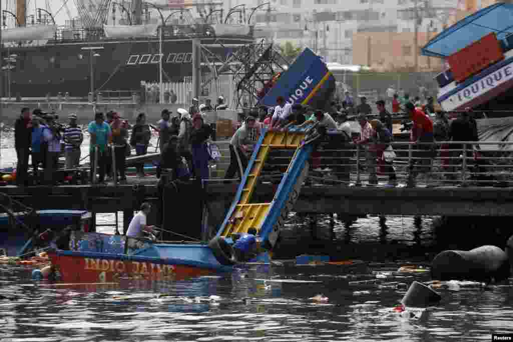 Para nelayan memeriksa kerusakan yang disebabkan gempa dan tsunami yang melanda pelabuhan Iquique di Chile utara (2/4).