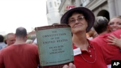 FILE - A woman holds a copy of the U.S. Constitution during a rally in New Orleans after two Supreme Court decisions supporting gay rights were handed down, June 26, 2013.