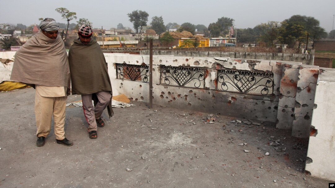 Dua warga India di pinggiran Jammu, India dekat perbatasan Pakistan, memeriksa rumahnya yang terkena tembakan dari Pakistan (3/1).