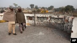 Indian villagers inspect the damage on the roof of a house, caused allegedly by firing from the Pakistan side of the border at Bainglad village in Samba sector, about 52 Kilometers from Jammu, India, Jan. 3, 2015.