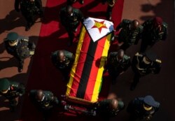 FILE - The casket of former President Robert Mugabe is escorted by military officers as it departs after a state funeral at the National Sports Stadium in Harare, Zimbabwe, Sept. 14, 2019.