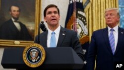 FILE - President Donald Trump looks to Secretary of Defense Mark Esper during a ceremony in the Oval Office at the White House in Washington.