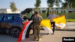 Voluntarios sostienen banderas iraquíes y vaticanas mientras decoran las calles de cara a la visita del Papa Francisco, en Qaraqosh, Iraq, el 22 de febrero del 2021.