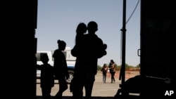FILE - Migrants, mainly from Central America, guide their children through the entrance of a World War II-era bomber hanger in Deming, N.M., May 22, 2019. Appeals court judges issued a ruling on conditions at the detention centers for children.