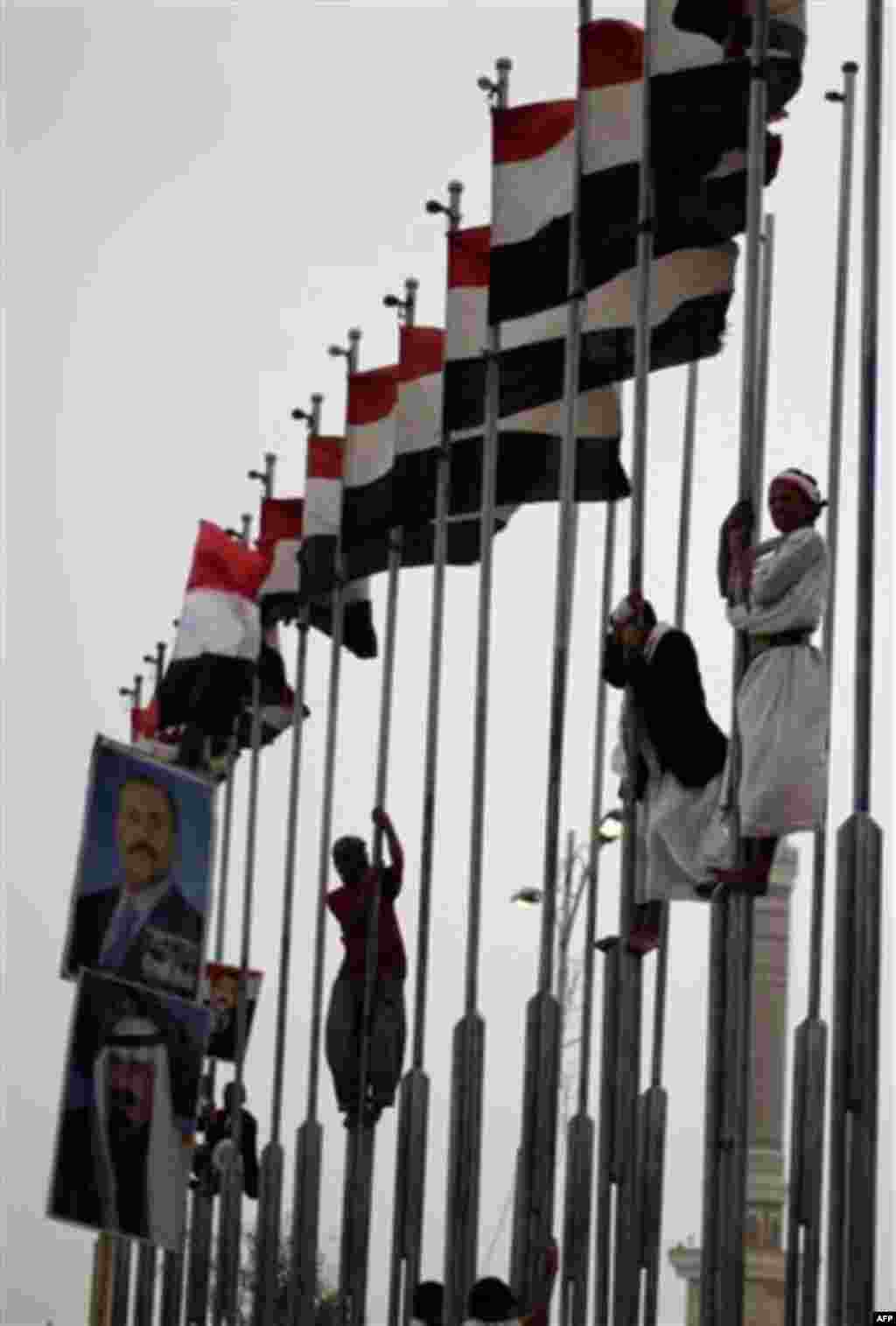 Supporters of Yemen's President Ali Abduallah Saleh stand on flag poles during a rally to show support for him in Sanaa, Yemen, Friday July 29, 2011. An uprising against Saleh's regime began six months ago. (AP Photo/Hani Mohammed)