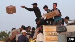 FILE—Palestinians carry boxes of humanitarian aid after rushing the trucks transporting the international aid from the US-built Trident Pier near Nuseirat in the central Gaza Strip on May 18, 2024.