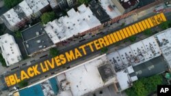 FILE- In this June 15, 2020, photo, a sign reading 'Black Lives Matter' is painted in orange on Fulton Street in the Brooklyn borough of New York. New York's mayor plans to paint the message in front of Trump Tower.