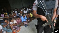 Polisi bersenjata berjaga-jaga dalam kunjungan Duta Besar Bangladesh untuk Indonesia Md. Nazmul Quaunine di tempat penampungan di Langsa, Aceh (17/5). (AP/Binsar Bakkara) 