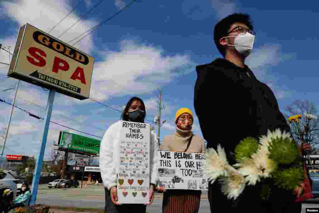 People hold signs during a demonstration at an informal memorial for victims of a mass shooting in Atlanta, Georgia, March 21, 2021.