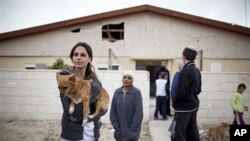 Israeli citizens stand next to a house that was damaged after a rocket fired by Palestinian militants from the Gaza Strip, landed in the southern Israeli town of Beersheba, March 23, 2011