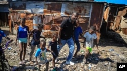 Jimmy Cherizier, the leader of the "G9 et Famille" gang, walks with children as he visits La Saline district of Port-au-Prince, Haiti, Jan. 24, 2023.