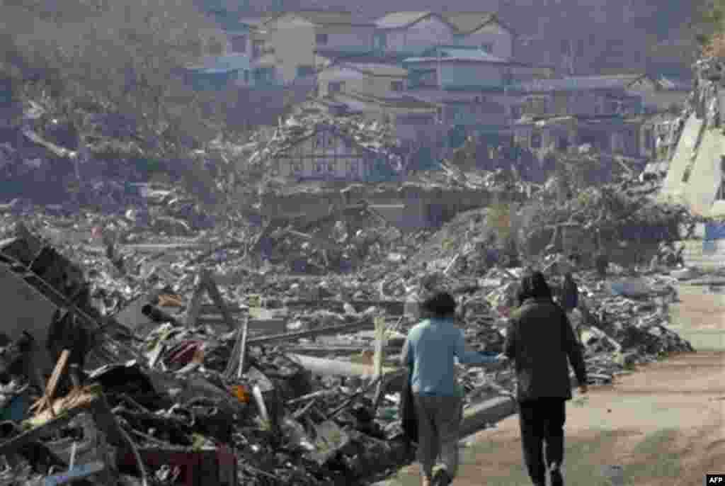 A couple walk along the rubble at a residential area in Onagawa, Miyagi Prefecture, northern Japan, Sunday, March 13, 2011, two days after a powerful earthquake-triggered tsunami hit the country's east coast. (AP Photo/The Yomiuri Shimbun) JAPAN OUT, CRED