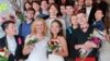 FILE - Two brides pose with their guests after their wedding ceremony at the wedding registry office in St. Petersburg, seemingly circumventing Russia's ban on same-sex marriages, Nov. 7, 2014. 