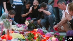 People mourn near the Olympia shopping center where a shooting took place the day before, leaving nine people dead in Munich, Germany, July 23, 2016. 