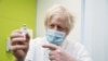 Britain's Prime Minister Boris Johnson holds a vial of AstraZeneca coronavirus vaccine during a visit to a coronavirus vaccination center at the Health and Well-being Centre in Orpington, South-East of London, Britain, Feb. 15, 2021.