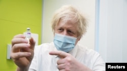 Britain's Prime Minister Boris Johnson holds a vial of AstraZeneca coronavirus vaccine during a visit to a coronavirus vaccination center at the Health and Well-being Centre in Orpington, South-East of London, Britain, Feb. 15, 2021.
