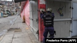 Seorang anggota kepolisian mengarahkan senjatanya ke arah sasaran setelah baku tembak dengan anggota geng kriminal di kawasan kumuh Cota 905, di Caracas, Jumat, 9 Juli 2021. (Foto: Frederico Parra/AFP) 