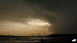 In this Wednesday, May 27, 2020 file photo, a boy stands on the shore of the Ganges River during a hot summer day in Prayagraj, India.