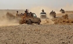 FILE - Fighters ride in pickup trucks as forces loyal to Yemen's Saudi-backed government clash with Houthi rebels in al-Jadaan, in Yemen's Marib governorate, Nov. 22, 2020.