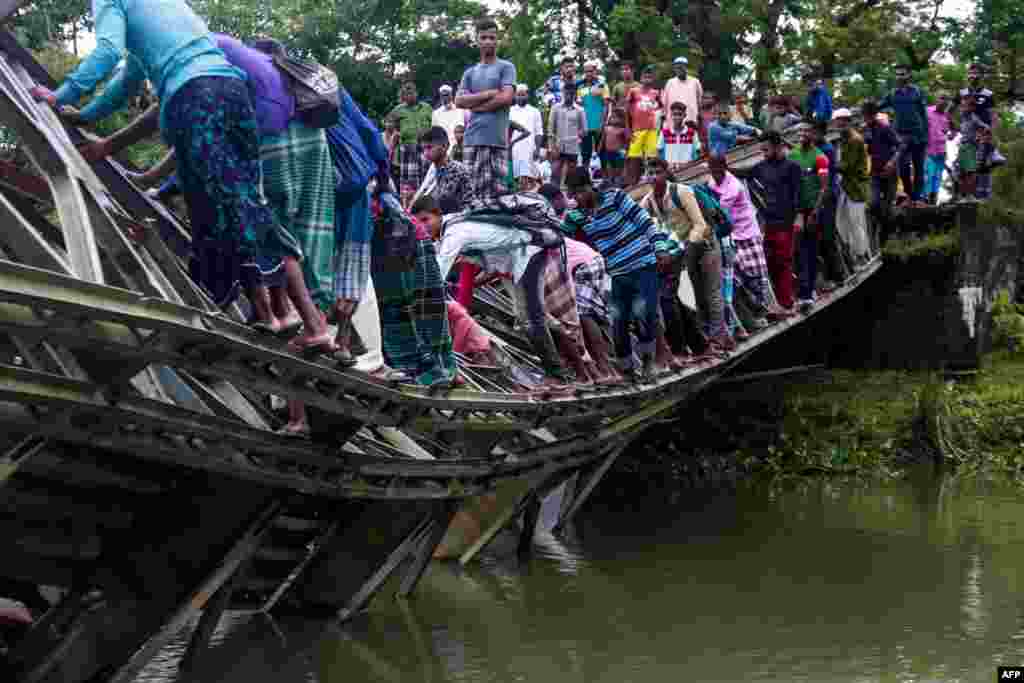 Pedestrians cross a broken bridge in Sylhet, Bangladesh, July 7, 2019.