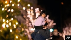 FILE - Family members pose for a photo by a Christmas tree on Christmas Eve in Tokyo, December 24, 2022. 