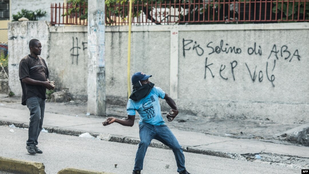  Yon manifestan kap tire wòch pandan yon mach opozisyon an nan Pòtoprens. 