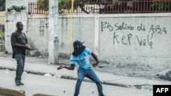 FILE - Protesters throw stones during an opposition demonstration commemorating the Battle of Vertieres Day in Port-au-Prince, Haiti. 