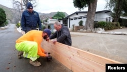 Ingenieros del servicio de campo en California instalan paneles de madera para proteger las casas de posibles inundaciones y deslizamientos de tierra debido a las malas condiciones metereológicas que amenazan varias regiones en California.