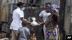 A health worker, center, distributes leaflets on how people should protect themselves from the new coronavirus, in Lagos, Nigeria, March 31, 2020.
