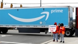 FILE - People hold a banner at the Amazon facility as members of a congressional delegation arrive to show their support for workers who will vote on whether to unionize, in Bessemer, Alabama, March 5, 2021.