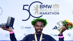 Pelari Ethiopia Milkesa Mengesha merayakan kemenangannya di podium setelah memenangkan Berlin Marathon ke-50 di Berlin, Jerman pada 29 September 2024. (Foto: AFP)