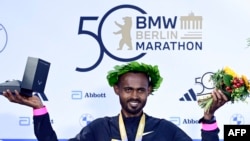 Pelari Ethiopia Milkesa Mengesha merayakan kemenangannya di podium setelah memenangkan Berlin Marathon ke-50 di Berlin, Jerman pada 29 September 2024. (Foto: AFP)