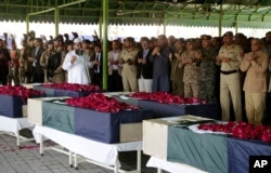 FILE - People pray at the funeral for victims of a bombing near a police checkpoint, in Lahore, Pakistan, March 15, 2018. The Taliban group Tehrik-e-Taliban Pakistan claimed responsibility for the bombing.