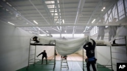 Workers, volunteers and Italian Army Alpini corps prepare the intensive care room of a new hospital being built in the spaces of the Bergamo Fair, in Bergamo, Italy, March 26, 2020.